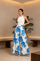 Woman wearing a white top and blue floral pants in an indoor setting.