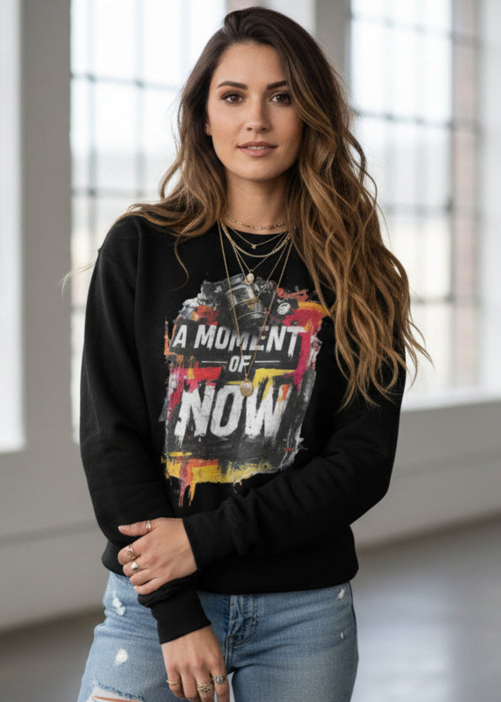 Woman wearing a black sweatshirt with colorful graphic design and text indoors.