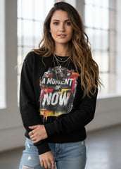 Woman wearing a black sweatshirt with colorful graphic design and text indoors.